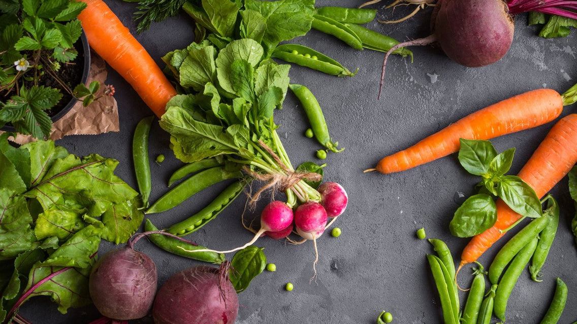 An overhead shot of several harvested vegetables and herbs showcasing what to plant April crops