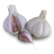 Two whole garlic bulbs with papery white and pale purple streaked skins, one split open to reveal plump pink-tinged cloves, beside a single loose clove.